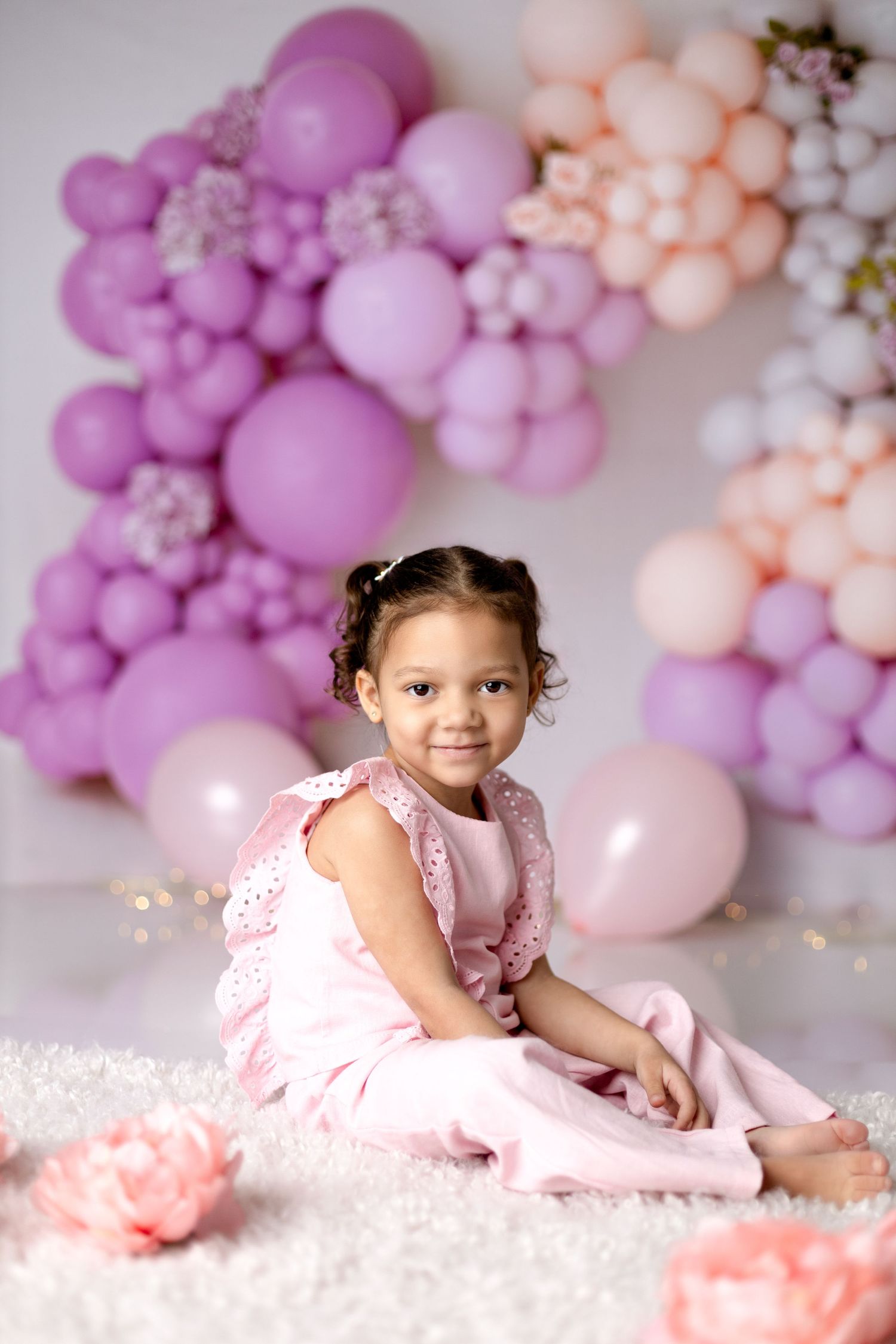 Pink balloon arch with sparkly lights creating festive backdrop.