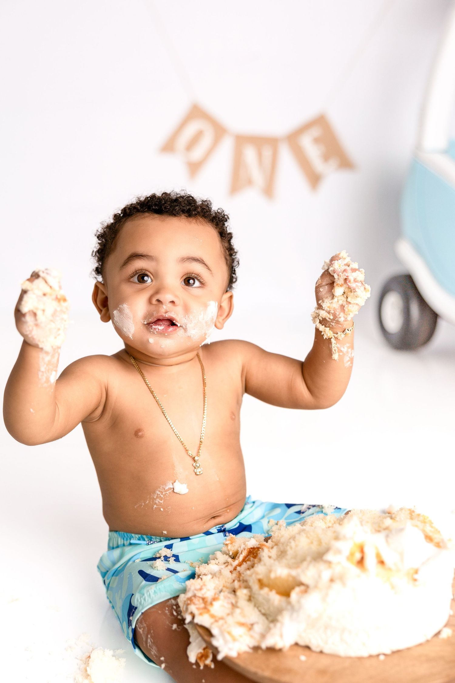 Cake smash photography session with baby enjoying messy vanilla frosting.