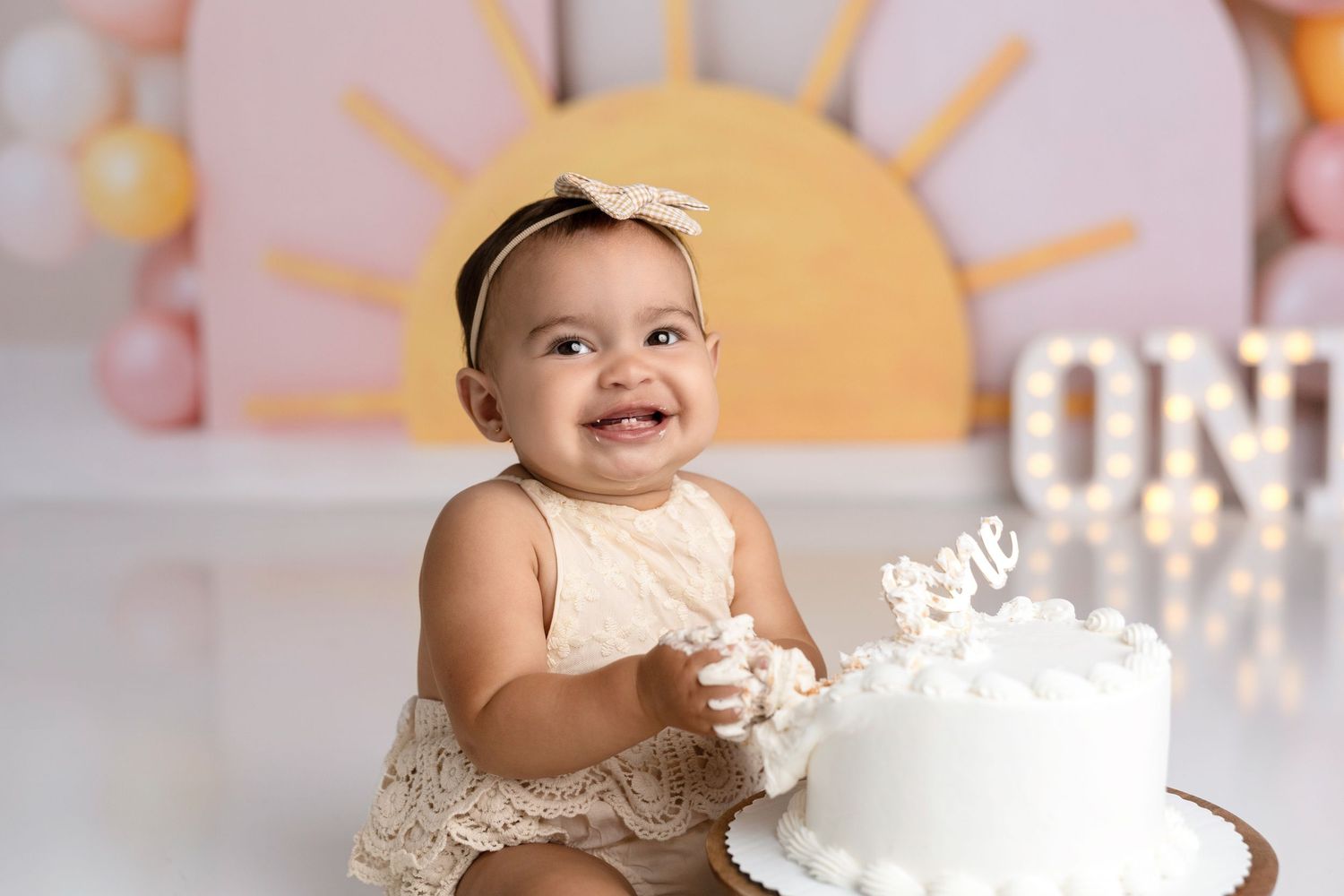 A series of baby milestone photos with pink and orange balloon decorations in the background.