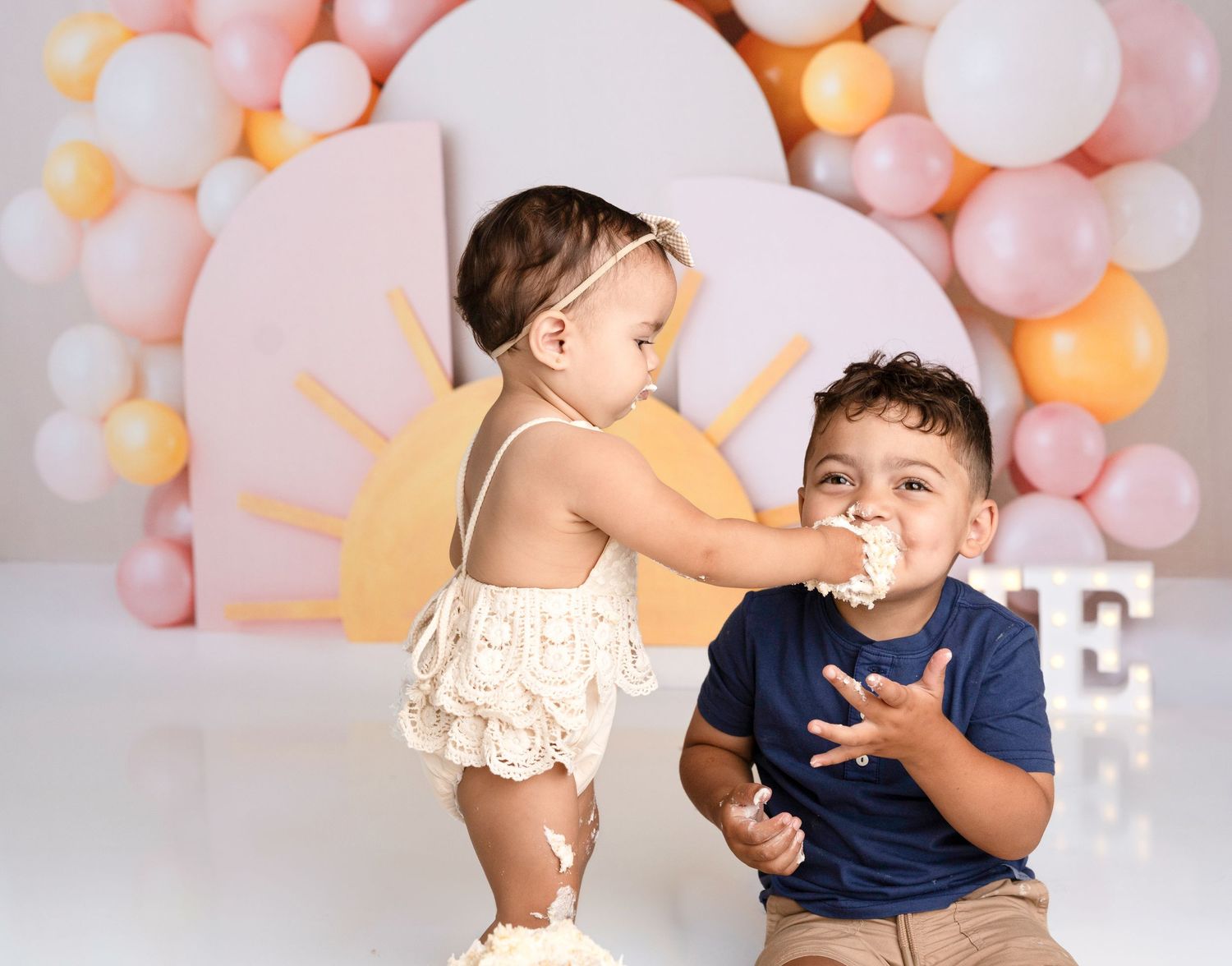 Children playing and posing during a photo session with pink balloon decorations.