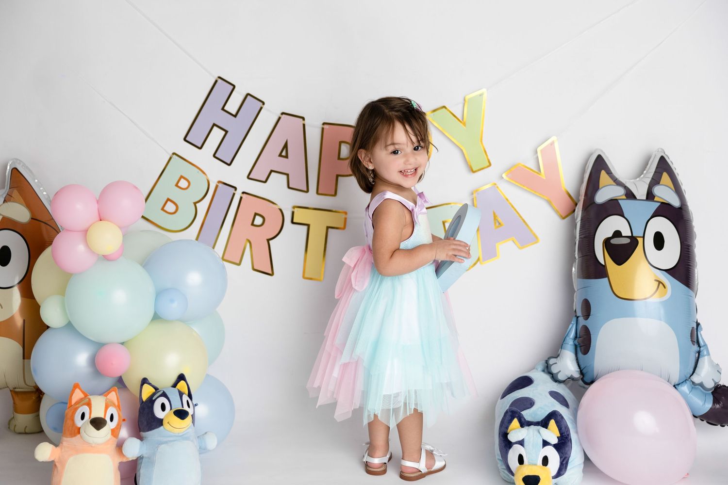 Colorful birthday party setup with pastel balloons and cute stuffed animal decorations.