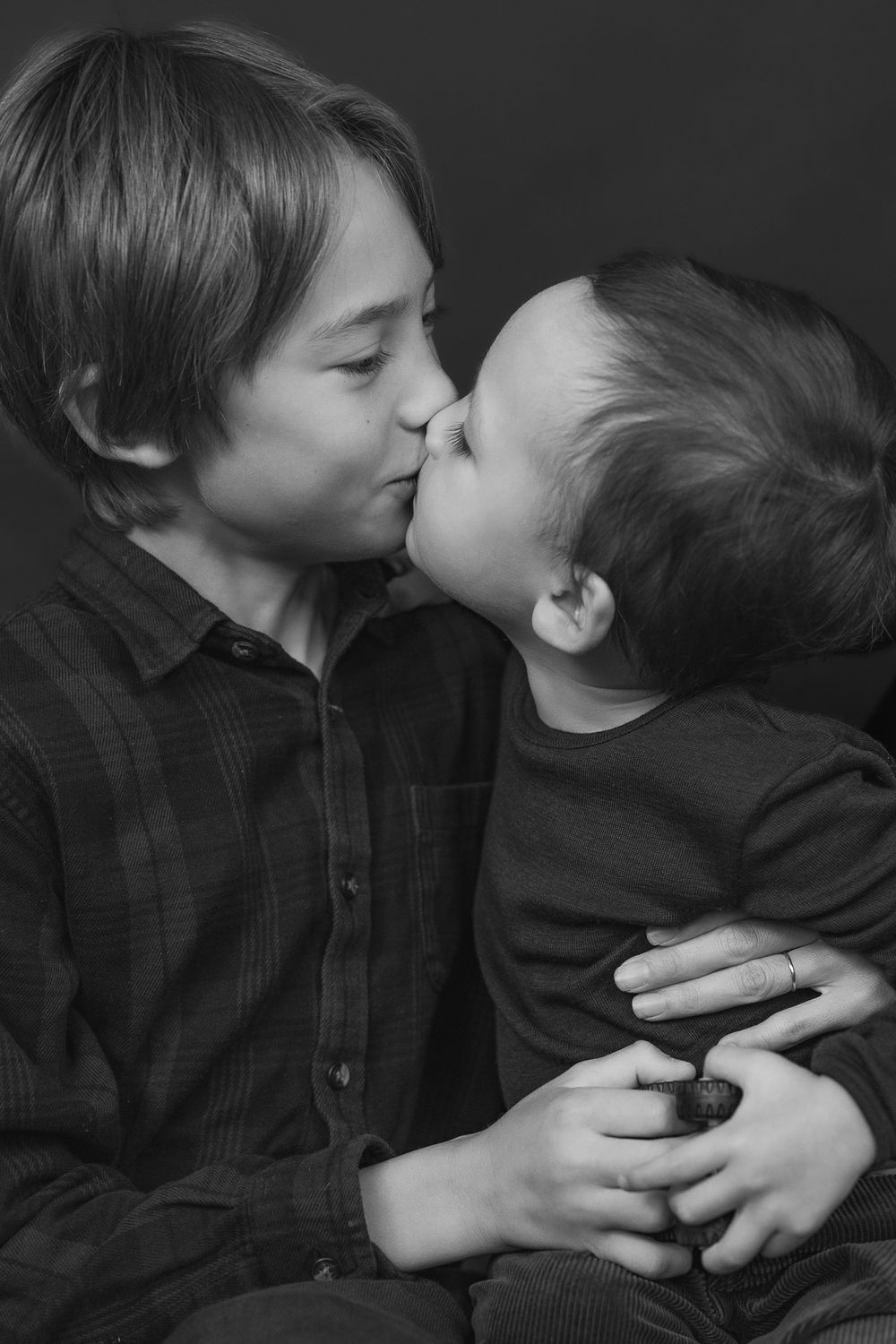 A series of black and white photos showing two children sharing a sweet kiss.