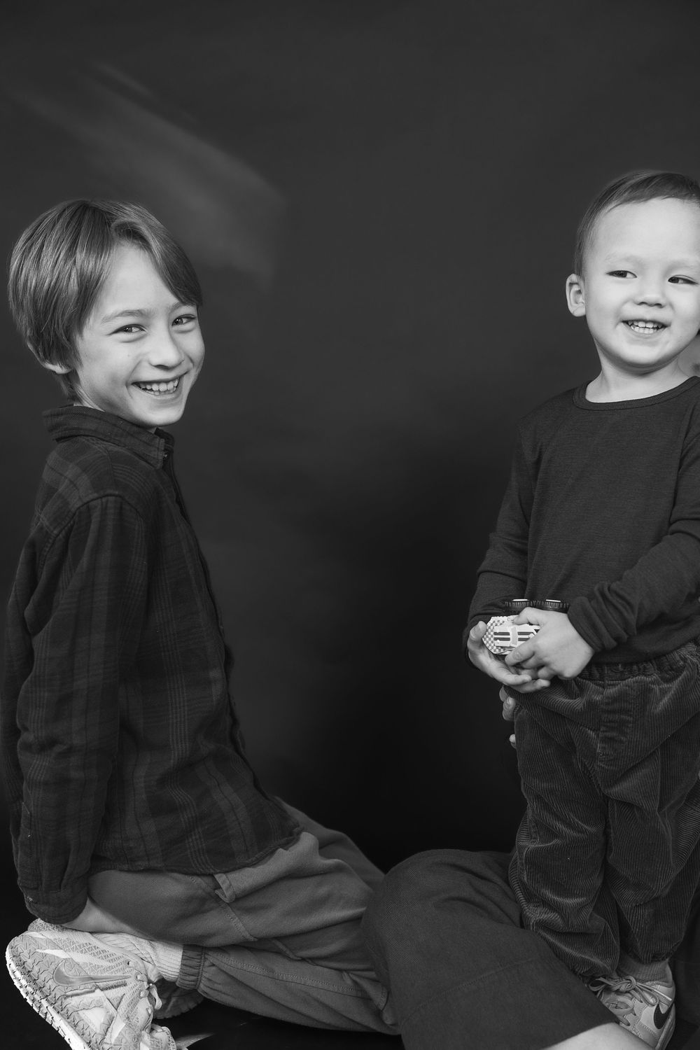 Black and white photo sequence showing someone in dark clothing sitting and turning against a dark background.