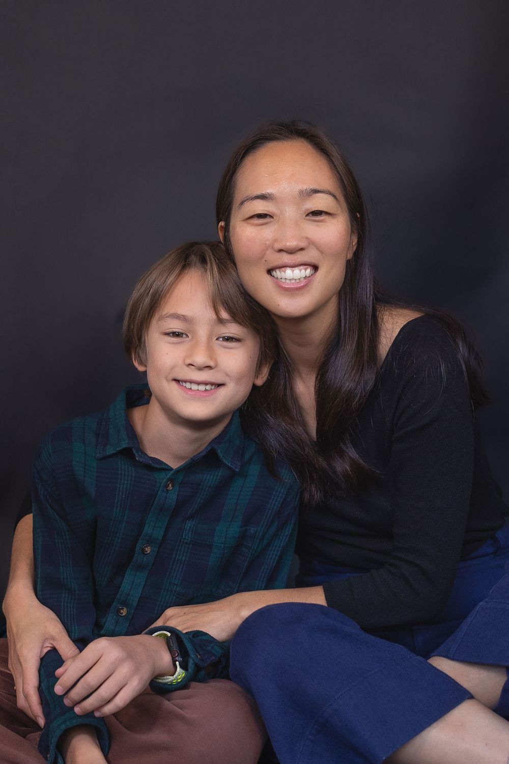 A family portrait session showing warm smiles and casual poses against a dark background.