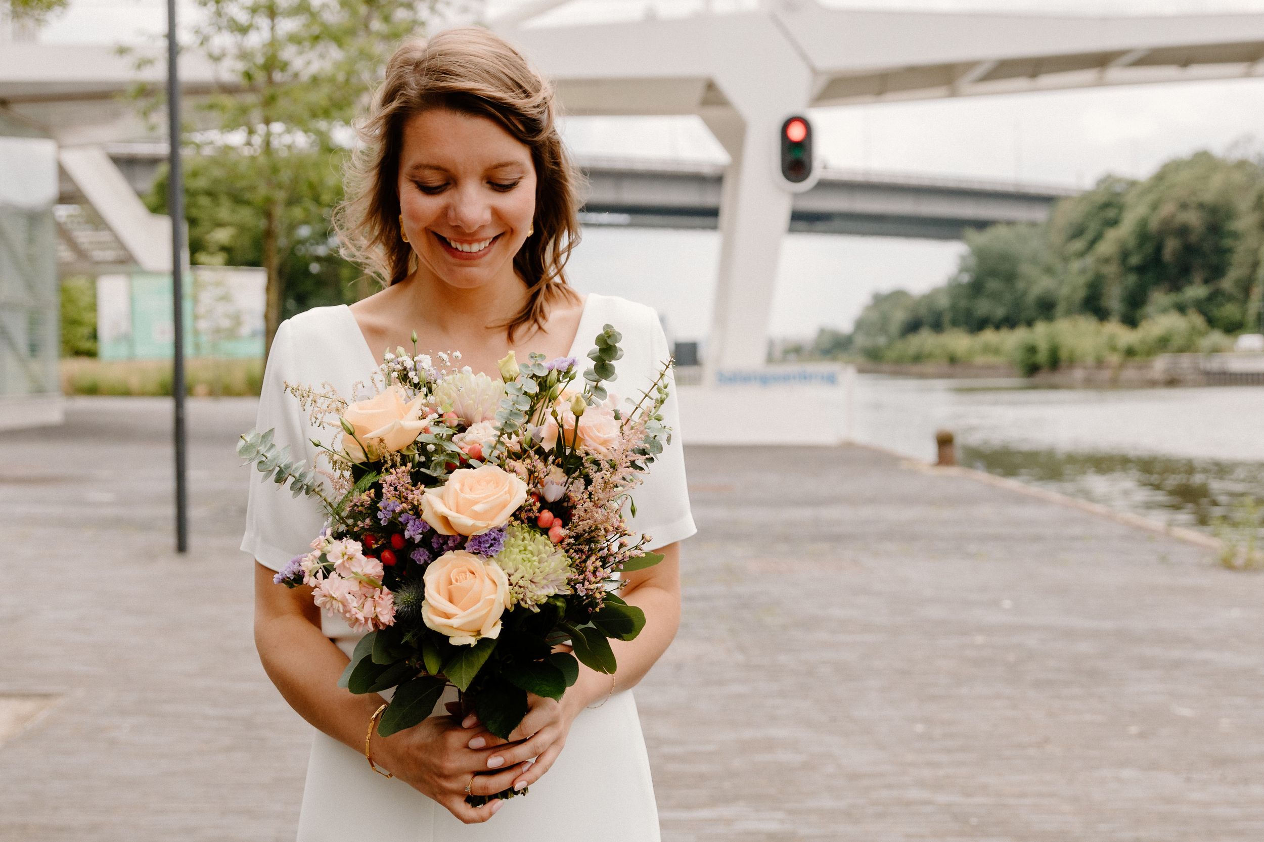 Wedding party members hold beautiful floral bouquets on an outdoor plaza.
