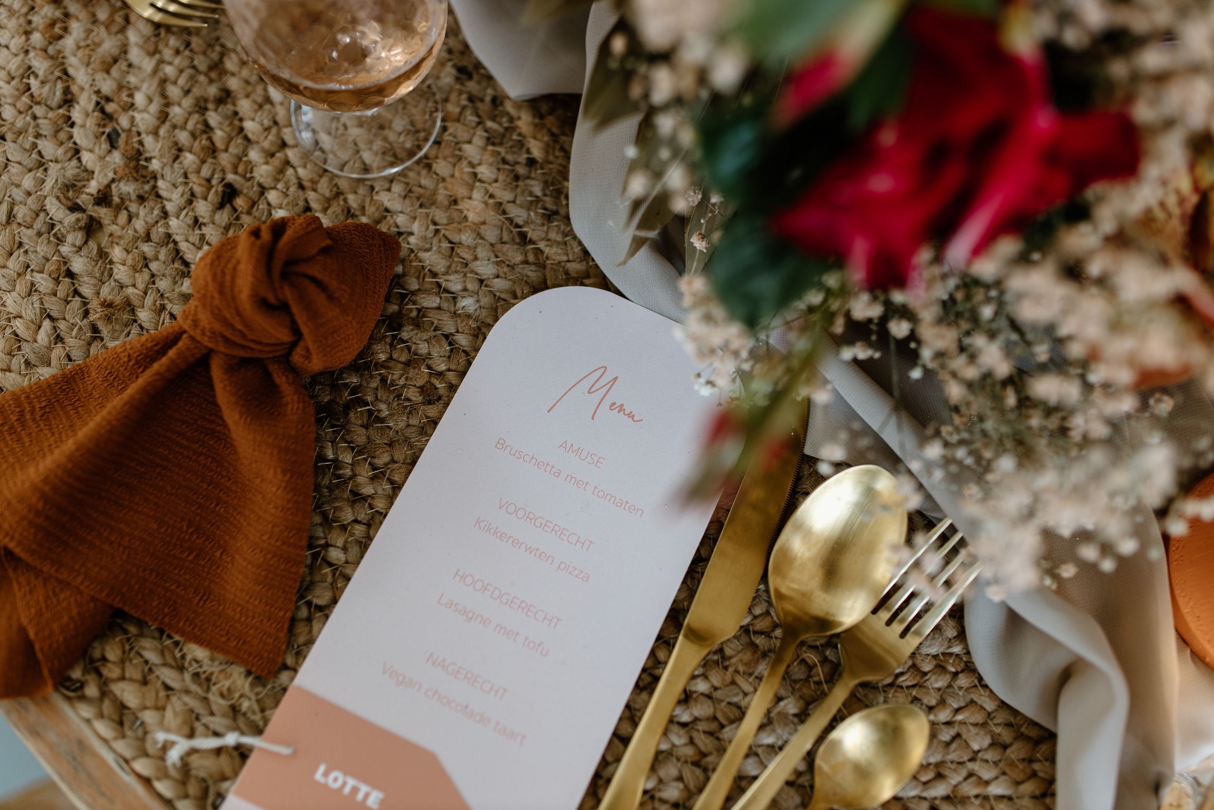 Wedding details including brown leather shoes, invitations, and decorative elements arranged on a woven surface.