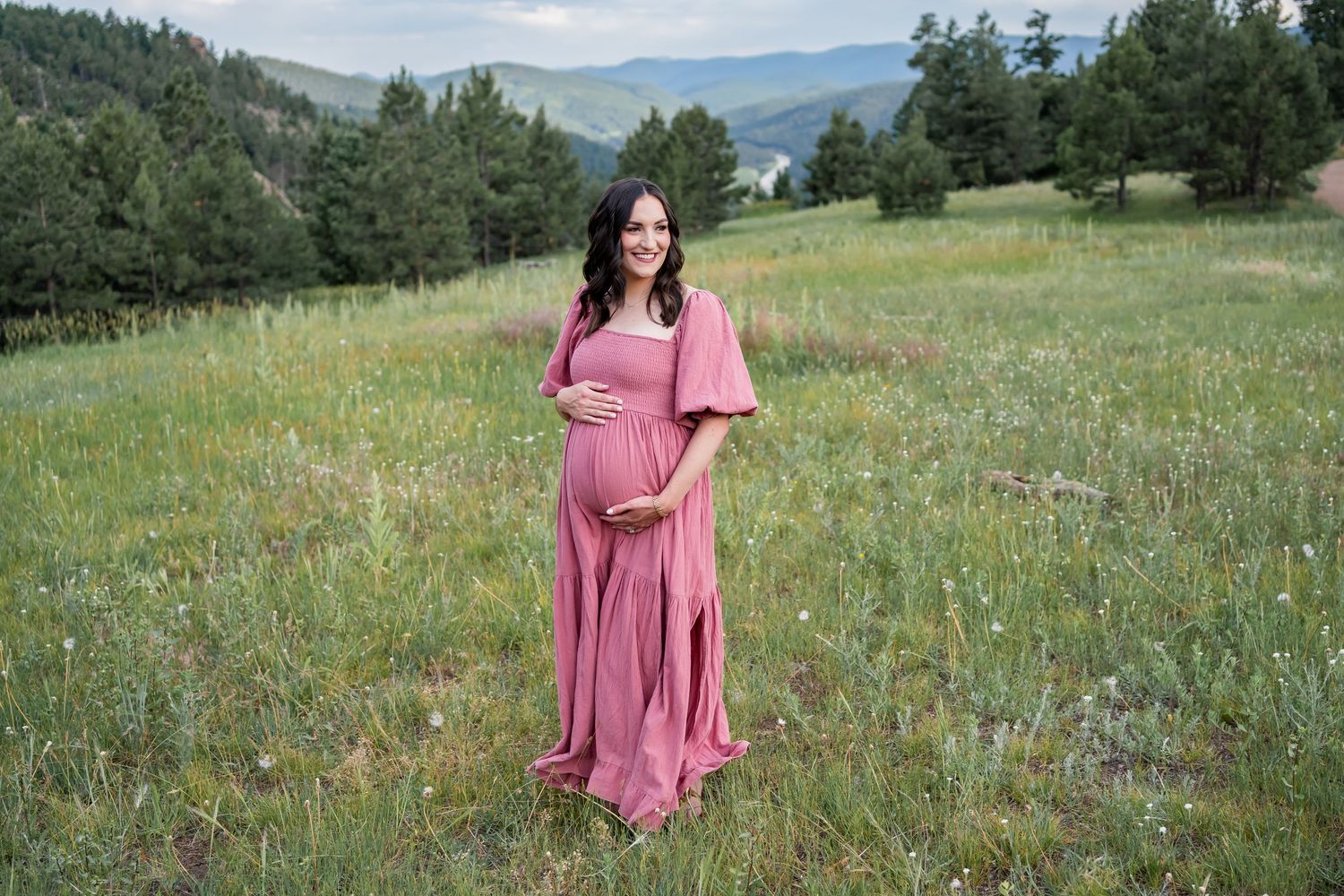 Maternity photo with flowing teal dress in minimalist studio setting.