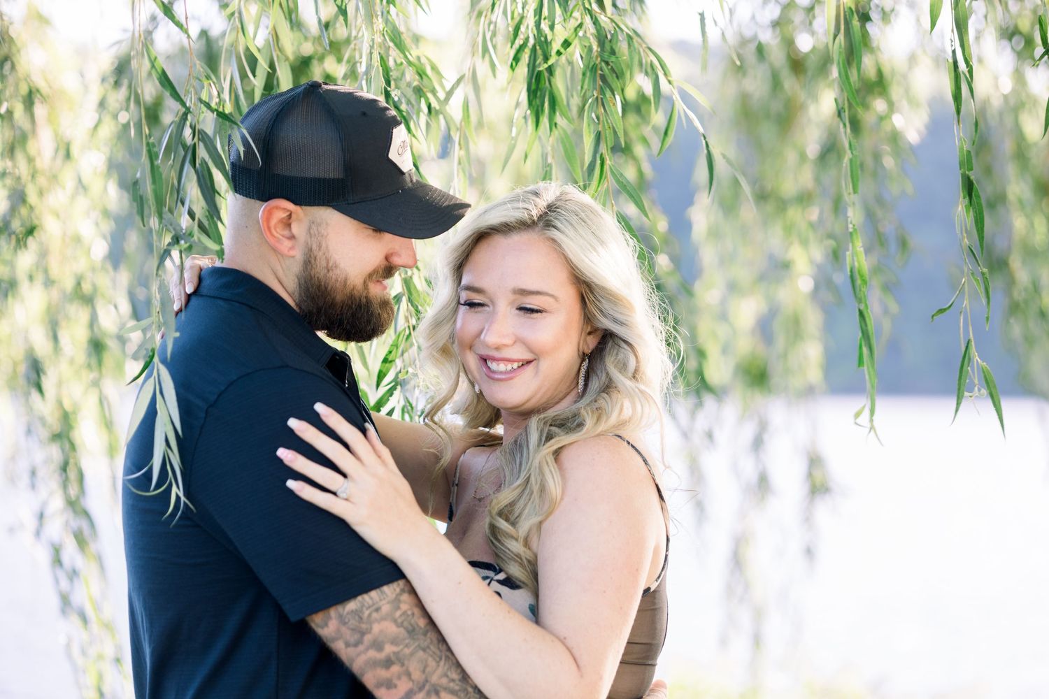 Romantic portraits of couple embracing under drooping willow branches.