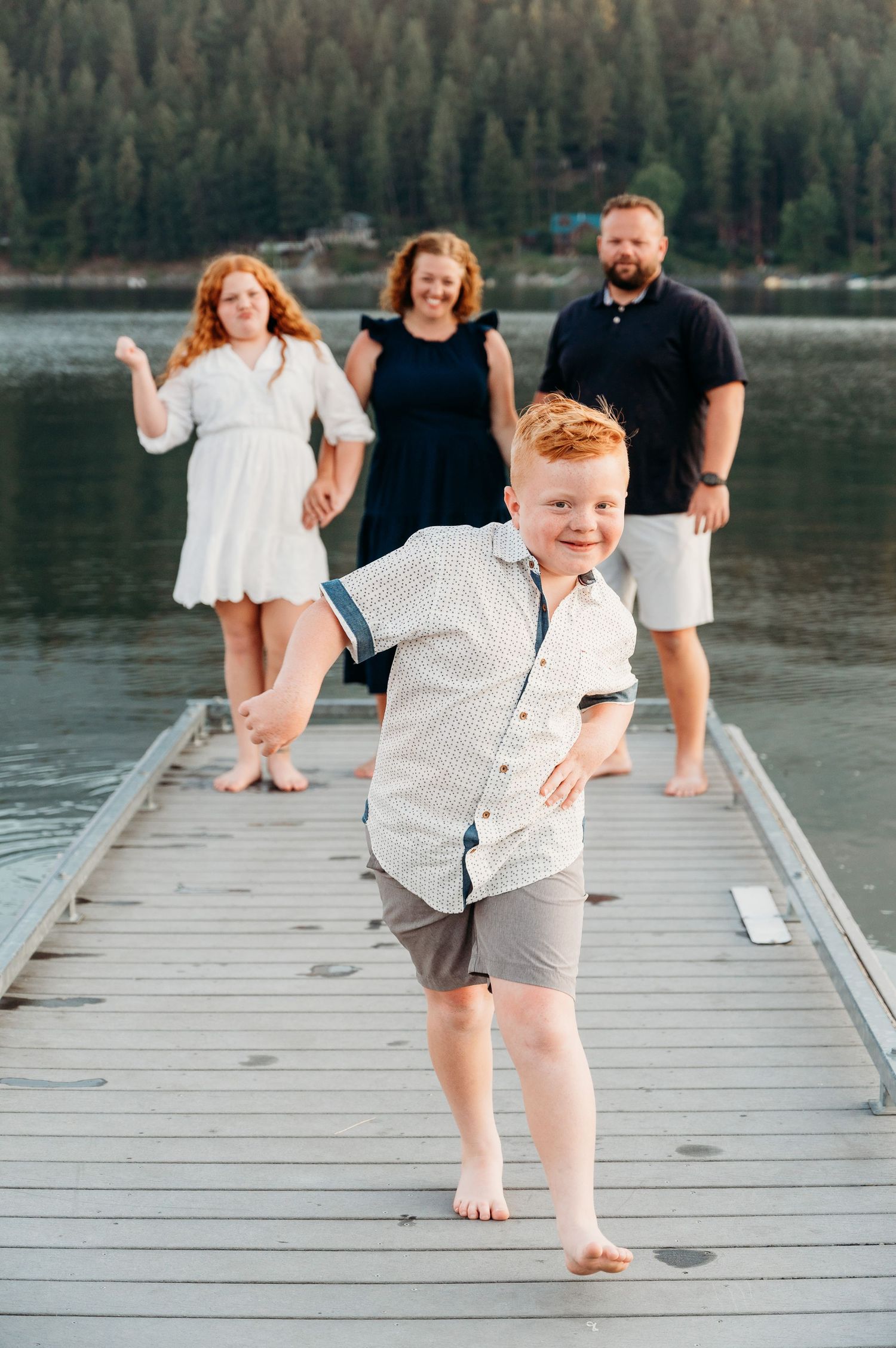 People posing playfully on a wooden dock by a serene mountain lake.  Wallowa Lake, Joseph, Oregon