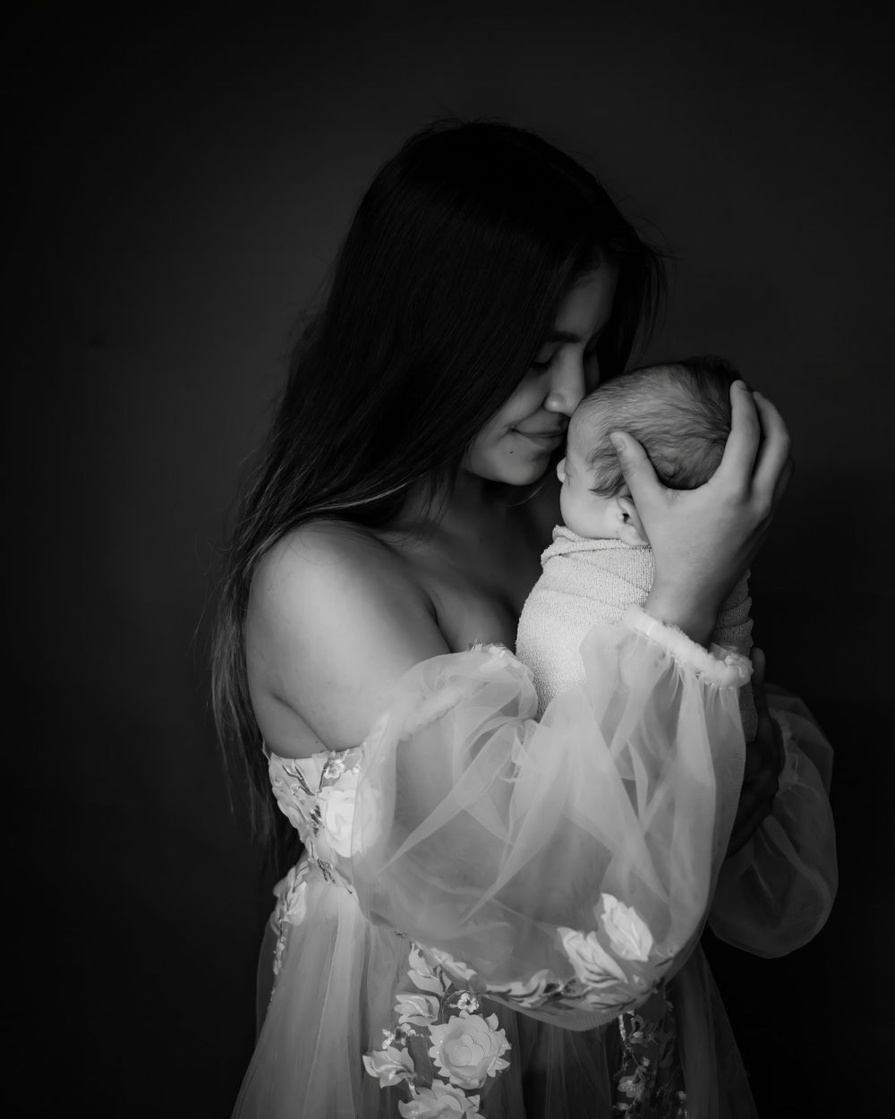 Intimate black and white portrait of mother cradling sleeping baby.