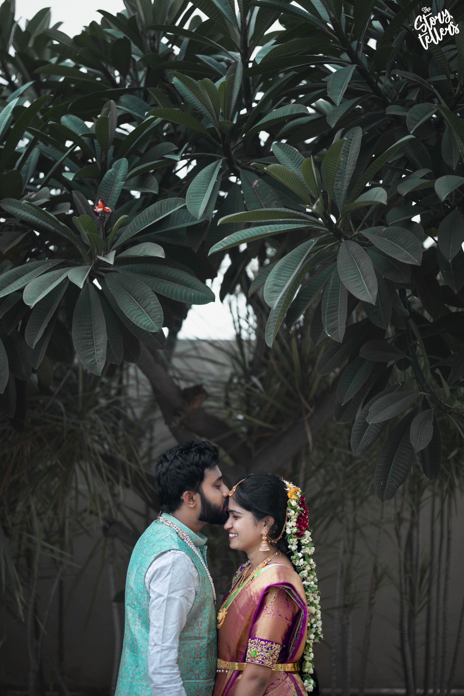 Intimate moment between couple under lush tropical foliage.