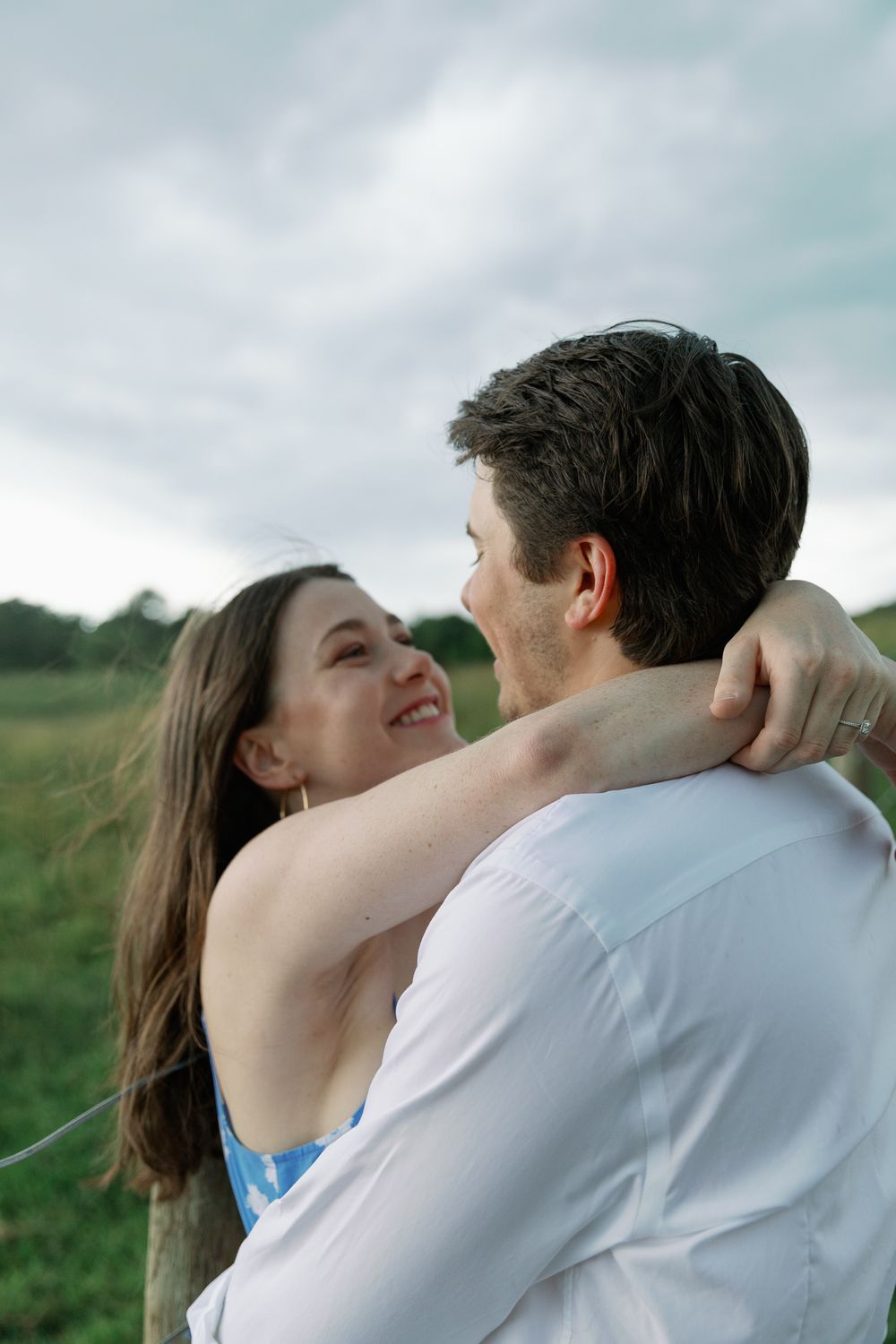 A couple sharing an intimate moment outdoors against a cloudy sky.