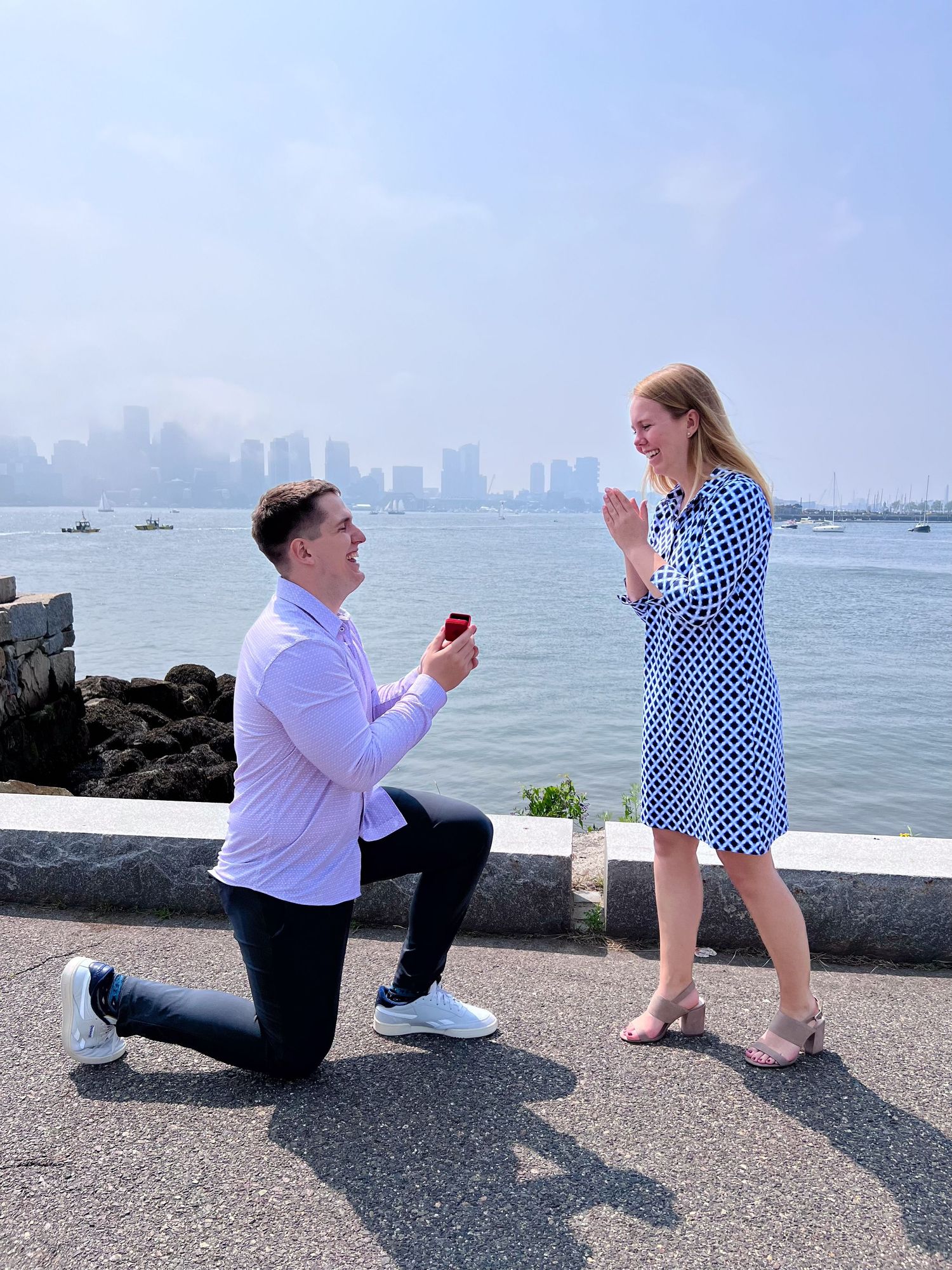 Marriage proposal on the East Boston waterfront with the Boston skyline in the backdrop of a man down on one knee - Leah Ramuglia Photograph