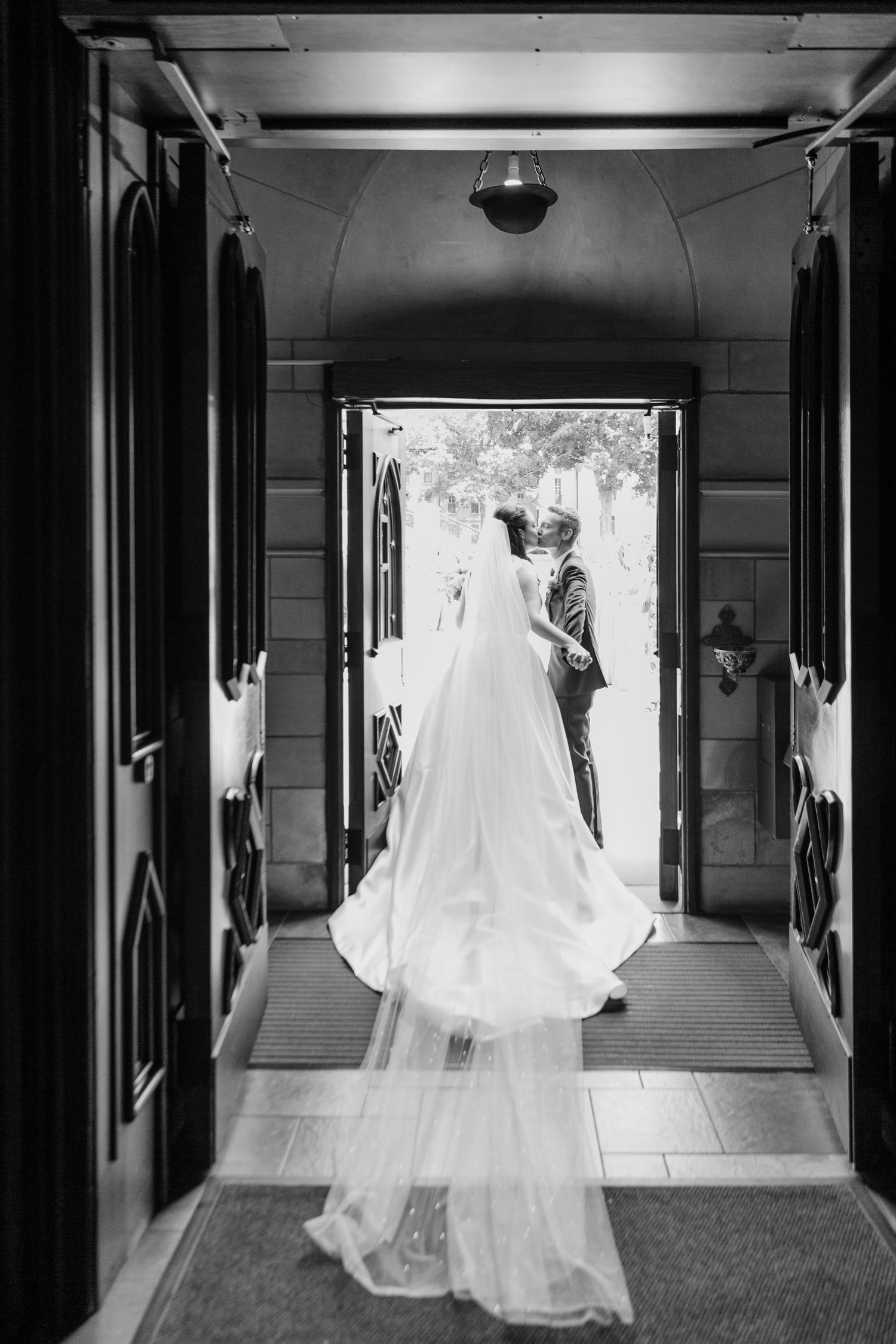 A flowing white wedding dress floats ethereally down a dark hallway in a series of artistic black and white photographs.