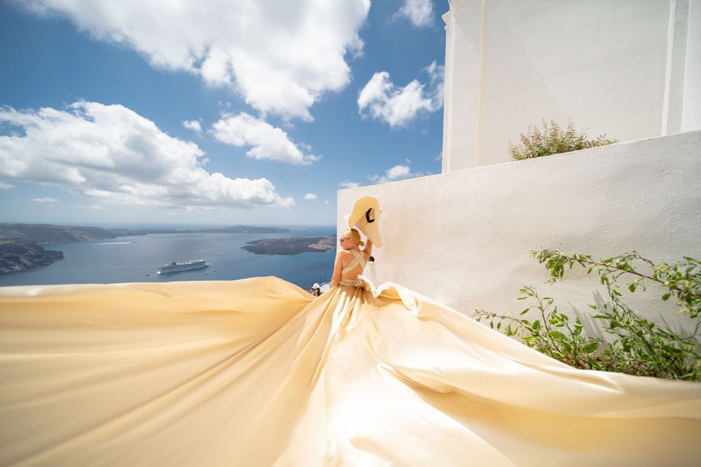 Champagne colored dress flowing dramatically against white walls and ocean views in Santorini.