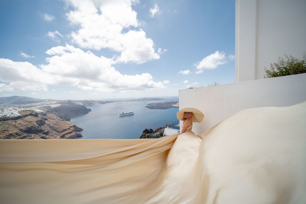 Flowing cream colored dress fabric captured against classic Santorini architecture and sea views.