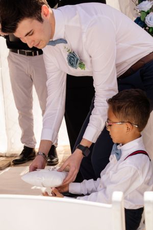 Young ring bearer signs wedding documents with guidance from an adult.