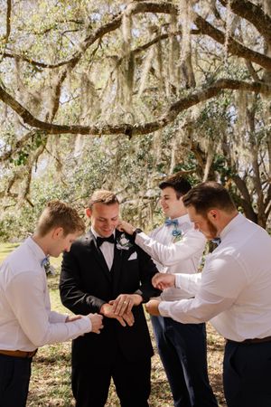 Wedding party members engage in a fun domino-effect photo sequence under moss-covered trees.
