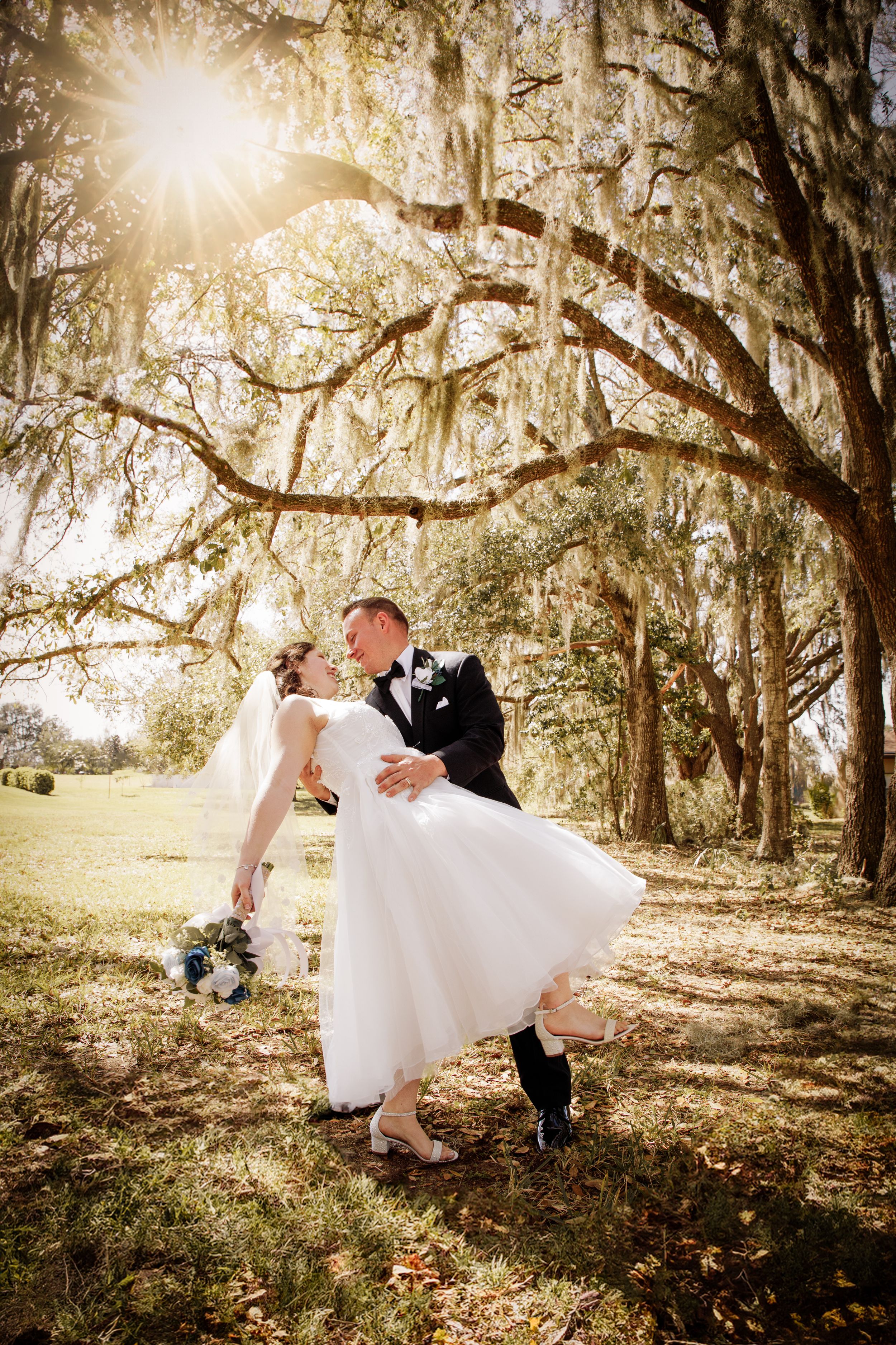 Romantic wedding poses captured under Spanish moss trees with dramatic lighting.