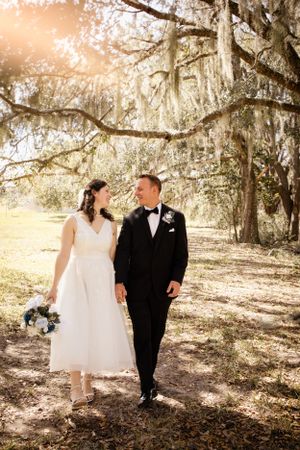 Romantic wedding photos taken under Spanish moss trees in warm sunlight.