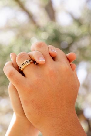 Close-up shots of hands with wedding rings intertwined against a natural backdrop.