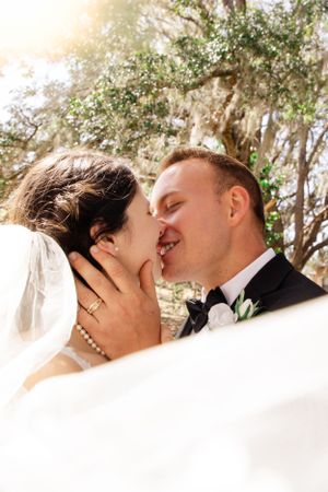 A romantic kiss sequence captured outdoors with trees in the background.