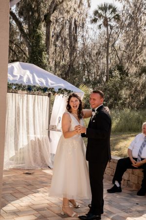 Wedding couple shares a joyful moment under white tent decorations.