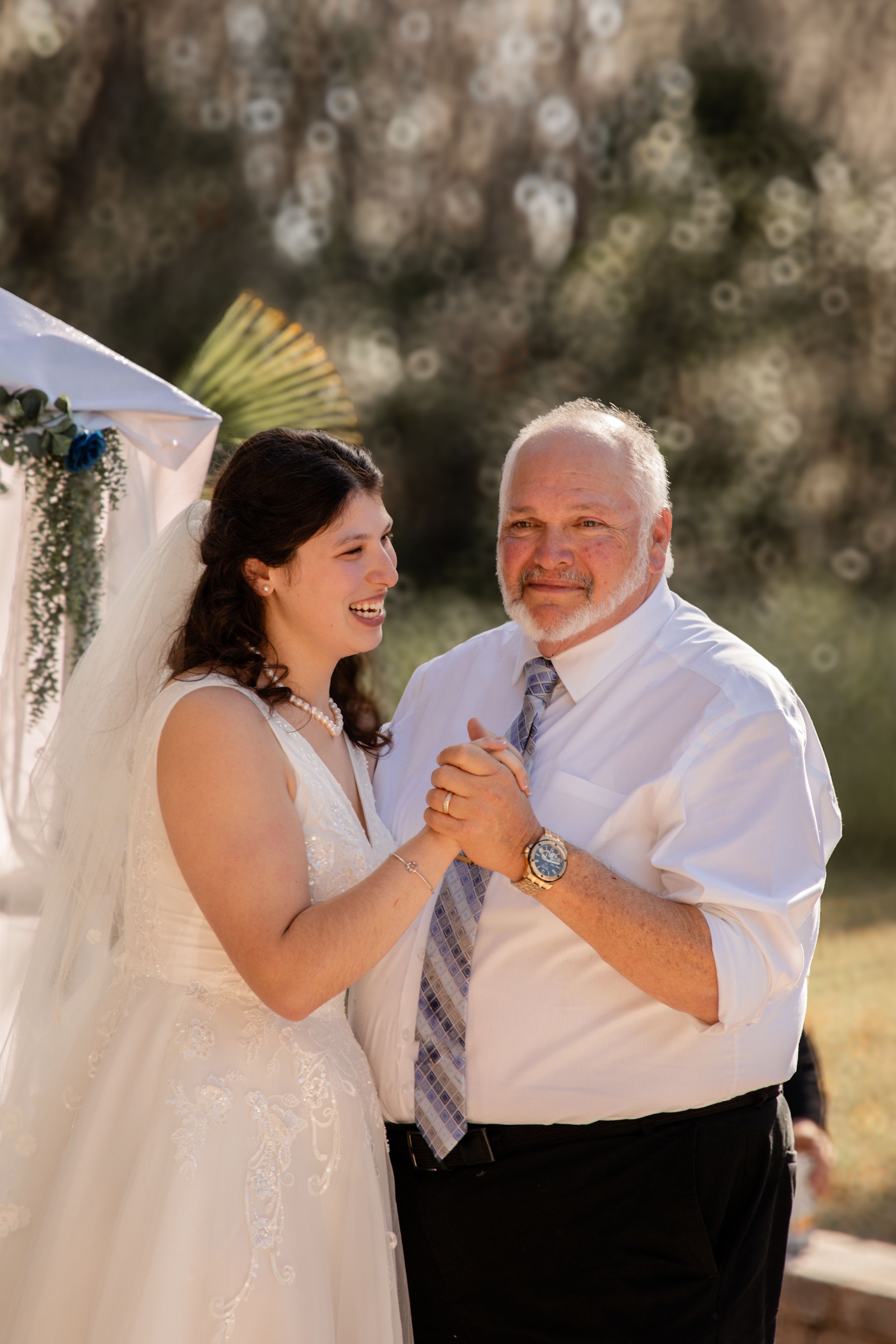 Bride and older gentleman share a dance at outdoor wedding reception.
