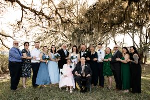 Large wedding party poses for group photo under Spanish moss covered trees.