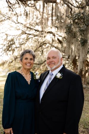 Couple in formal attire poses for portraits under Spanish moss trees.