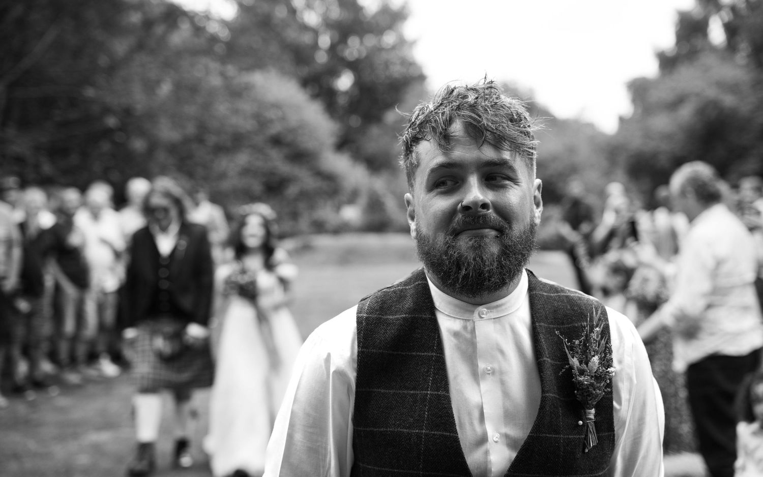 Smiling groom stands at alter waiting for bride