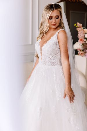 Bride wearing a white lace plunging neckline ball gown with tulle skirt and long veil.