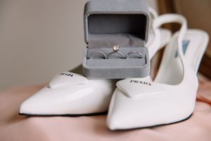 White Prada bridal shoes displayed with engagement ring in gray velvet box.