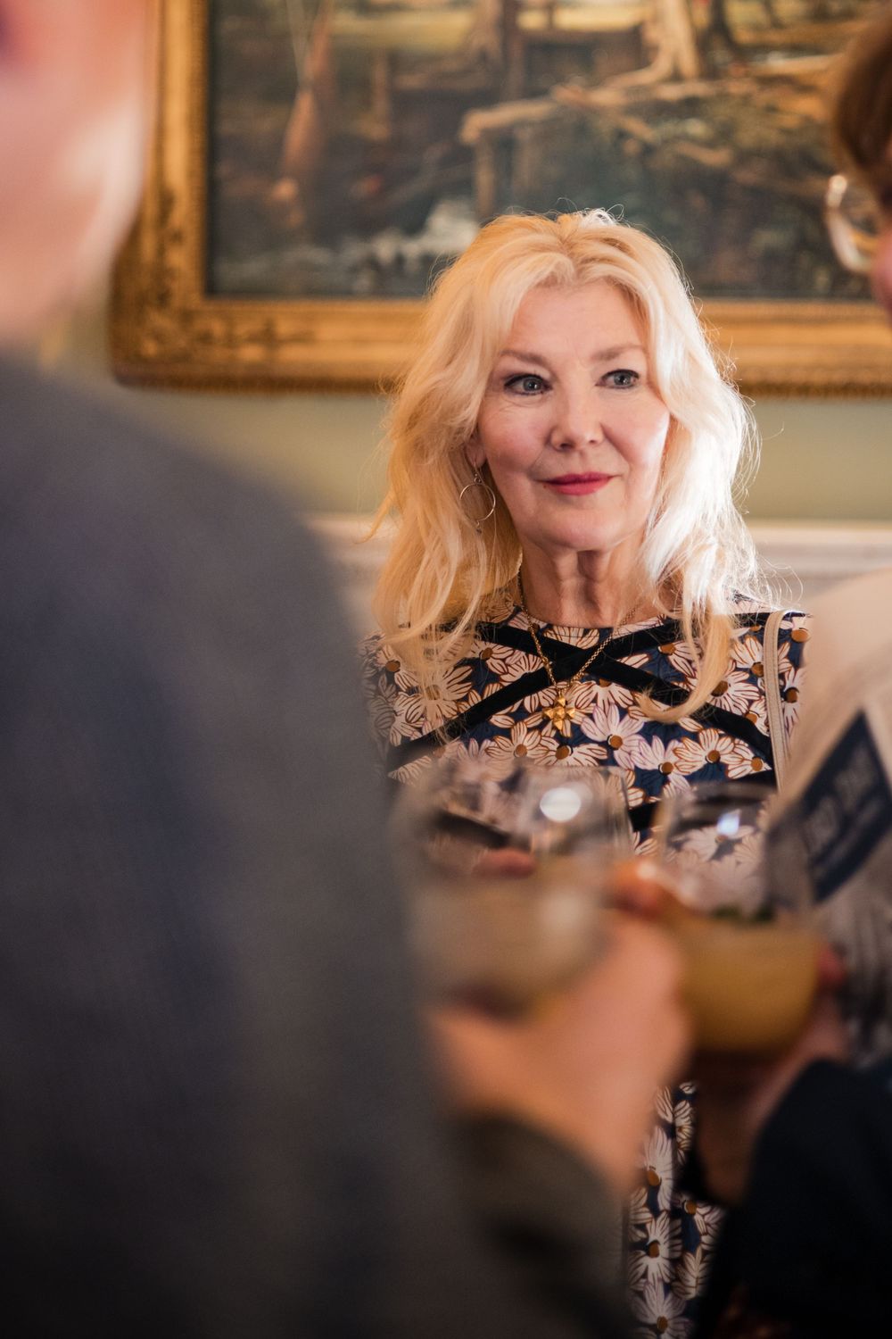 A glamorous guest in sparkling attire engages in conversation at an upscale event.