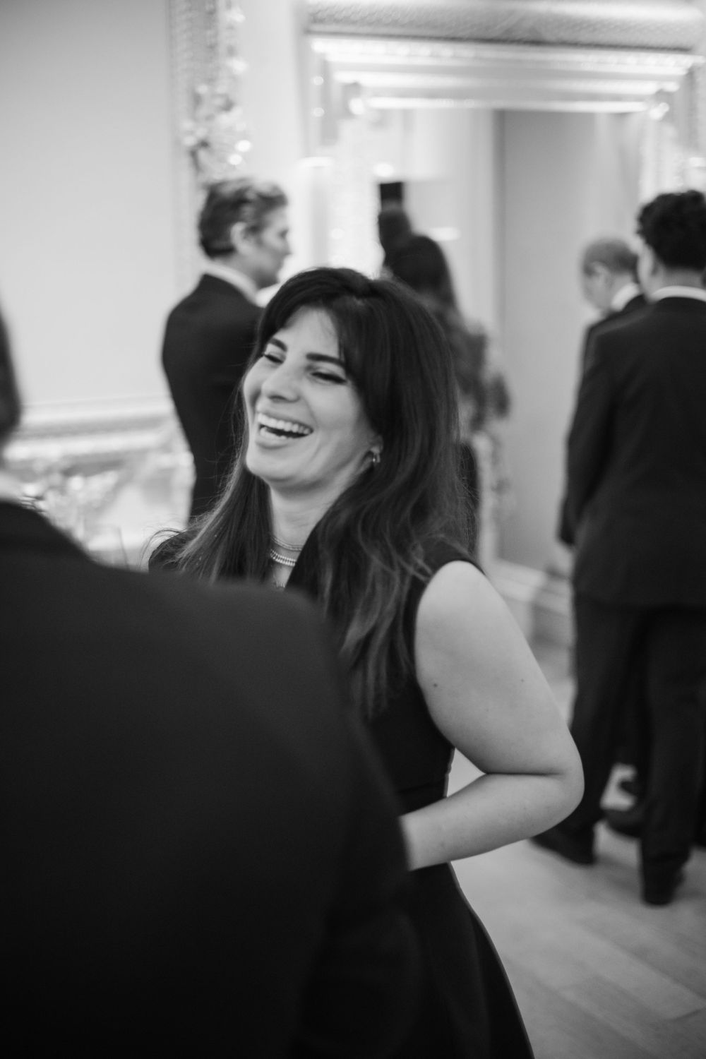 A black and white capture of genuine laughter during an elegant indoor celebration.