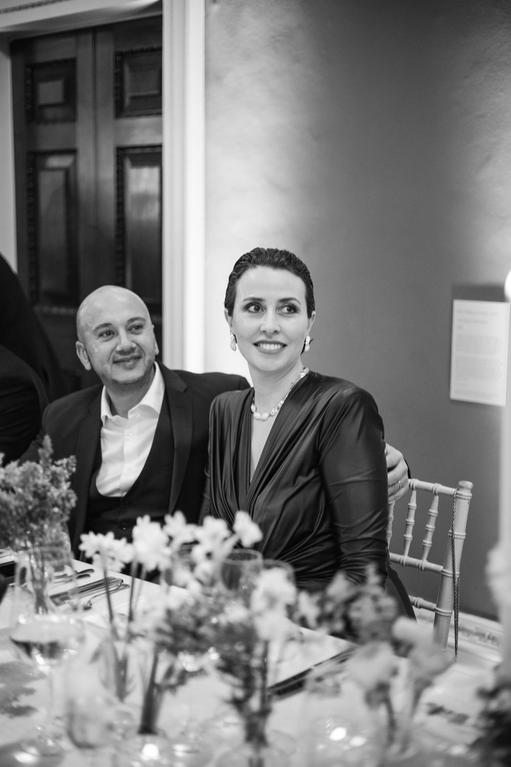 Guests seated at an elegant dinner table with floral centerpieces in black and white.