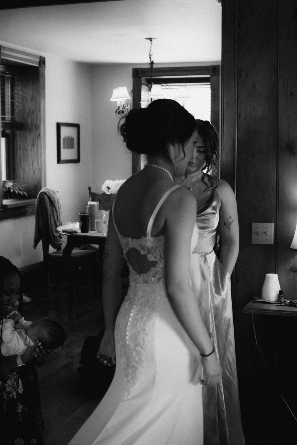 Black and white candid photo showing the back detail of a lace wedding dress.