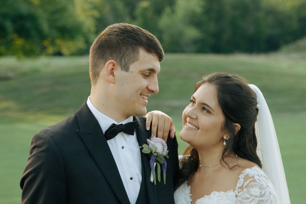A sweet moment between newlyweds sharing smiles in formal attire on their wedding day.