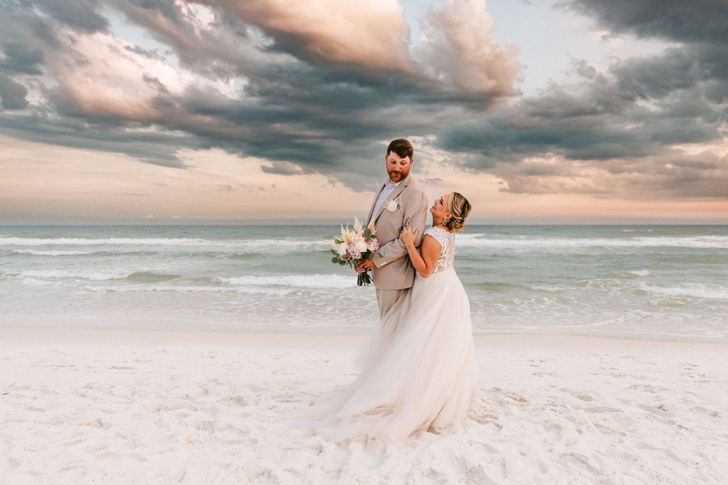 A wedding couple pose for their couples portraits on their wedding day at the beach in Destin, Florida.