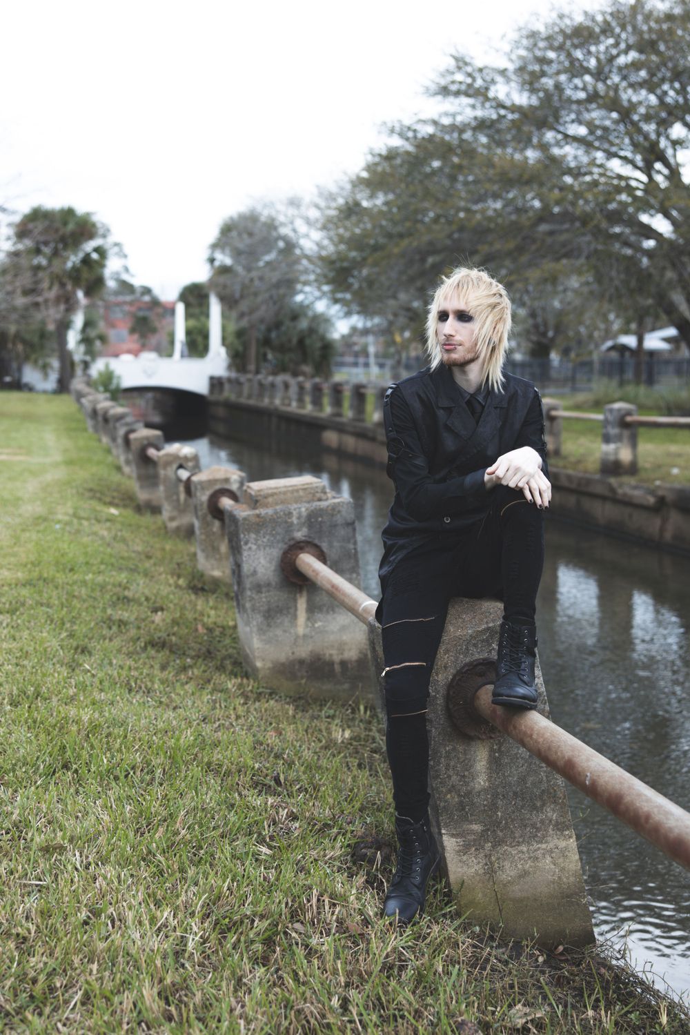Alternative style portrait in all black clothing posed along historic canal railing.