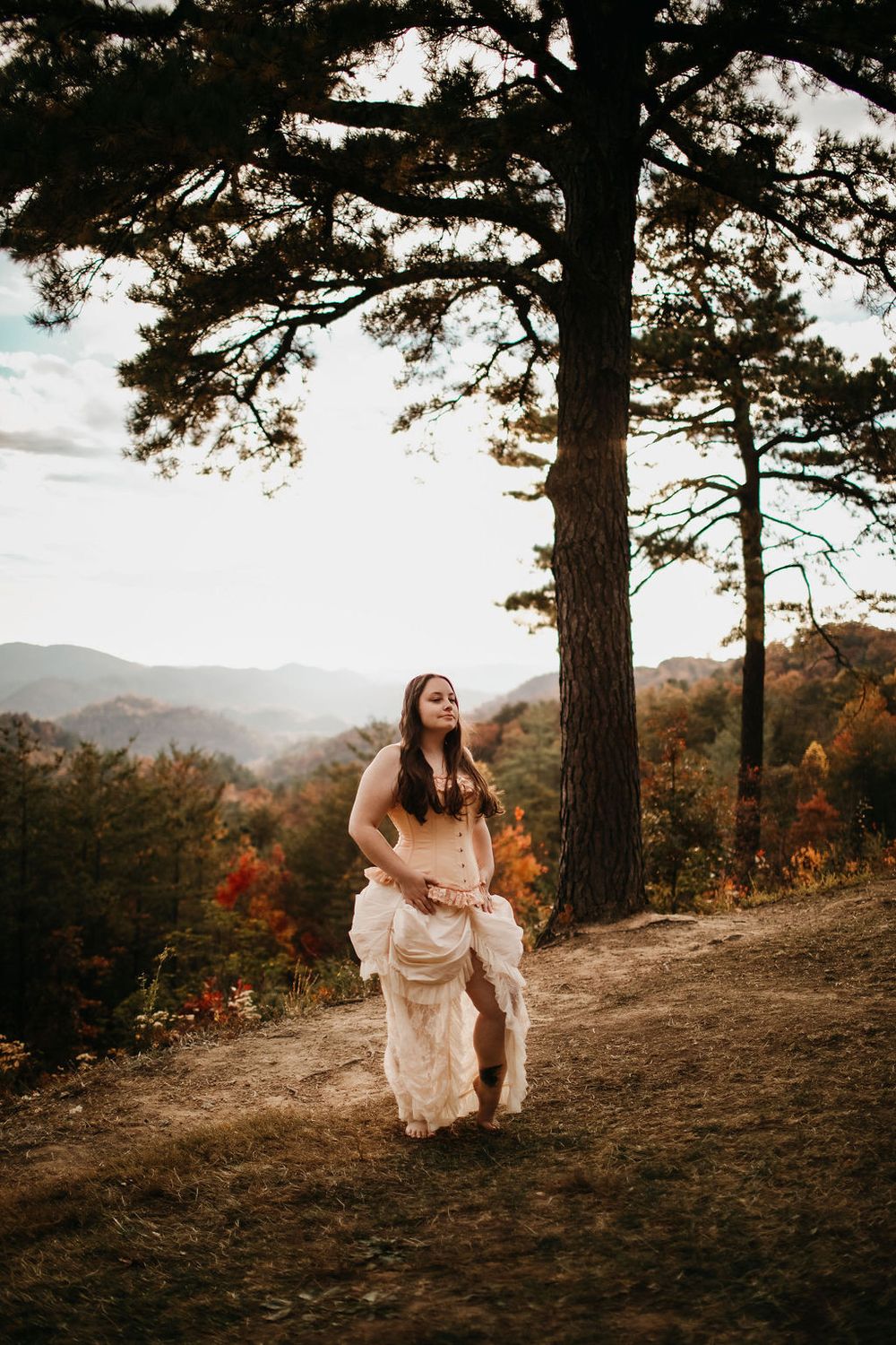 Scenic mountain overlook photo featuring vintage dress against fall foliage and pine trees.