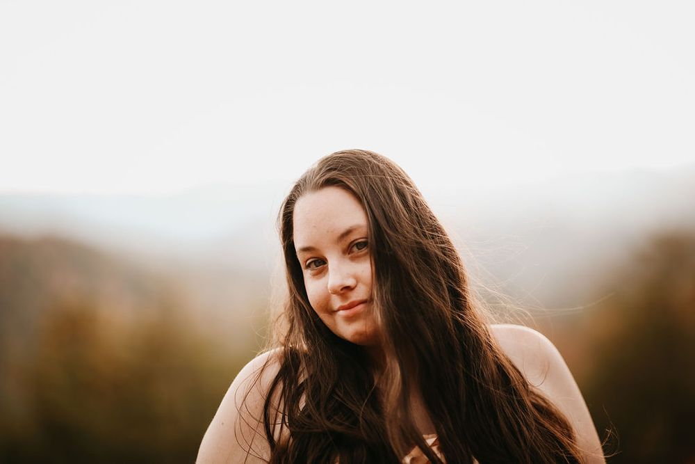 Close up portrait in warm autumn tones with blurred mountain backdrop.