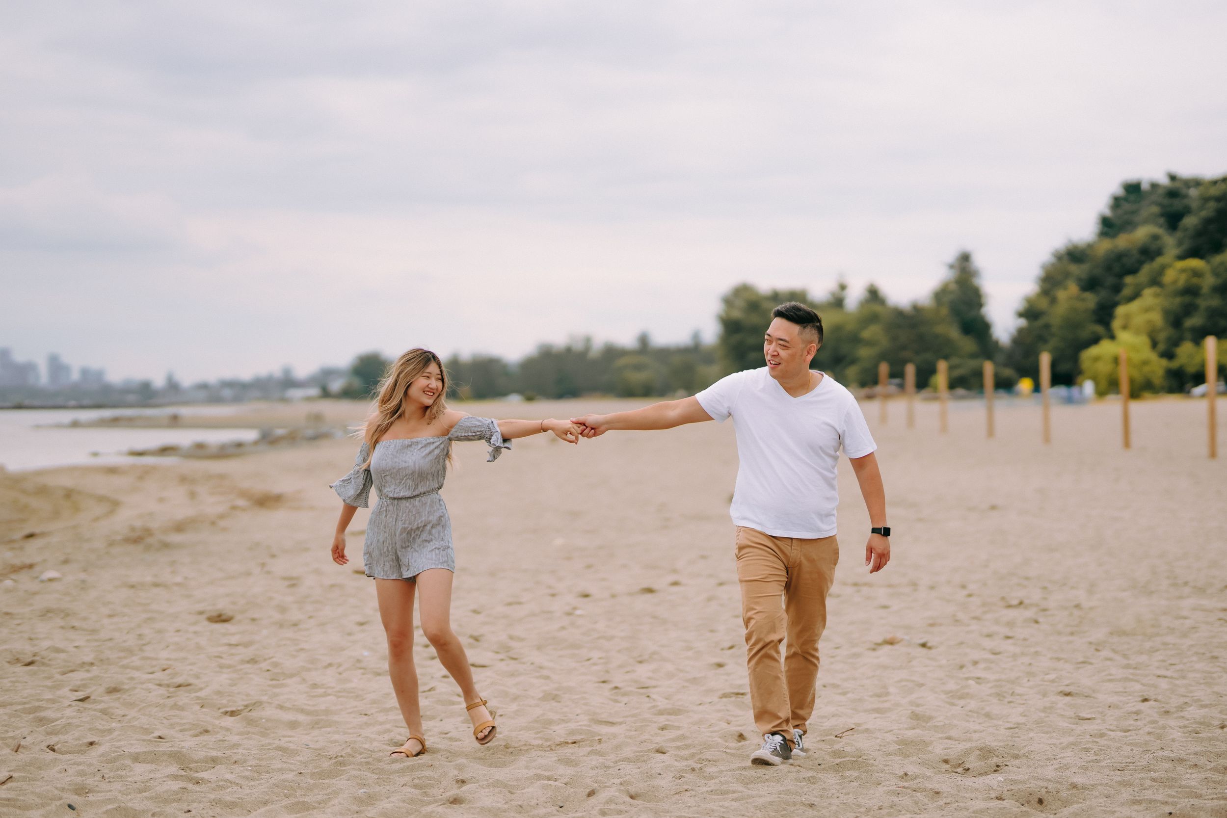Couple taking a relaxing stroll together on a sandy beach with ocean waves visible in the background.
