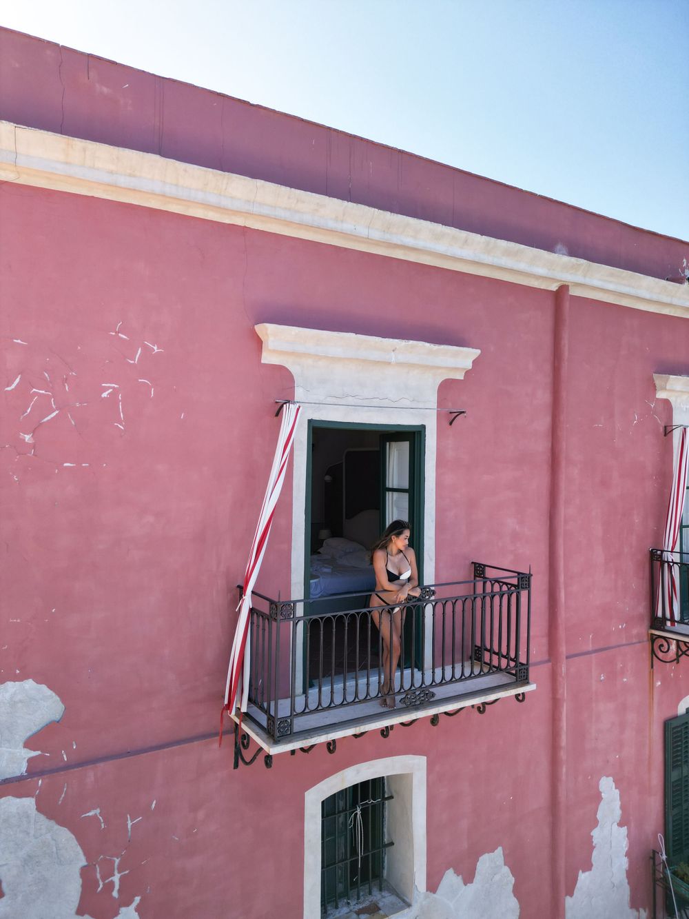 Historic pink colonial building with ornate balconies in a Mediterranean style.