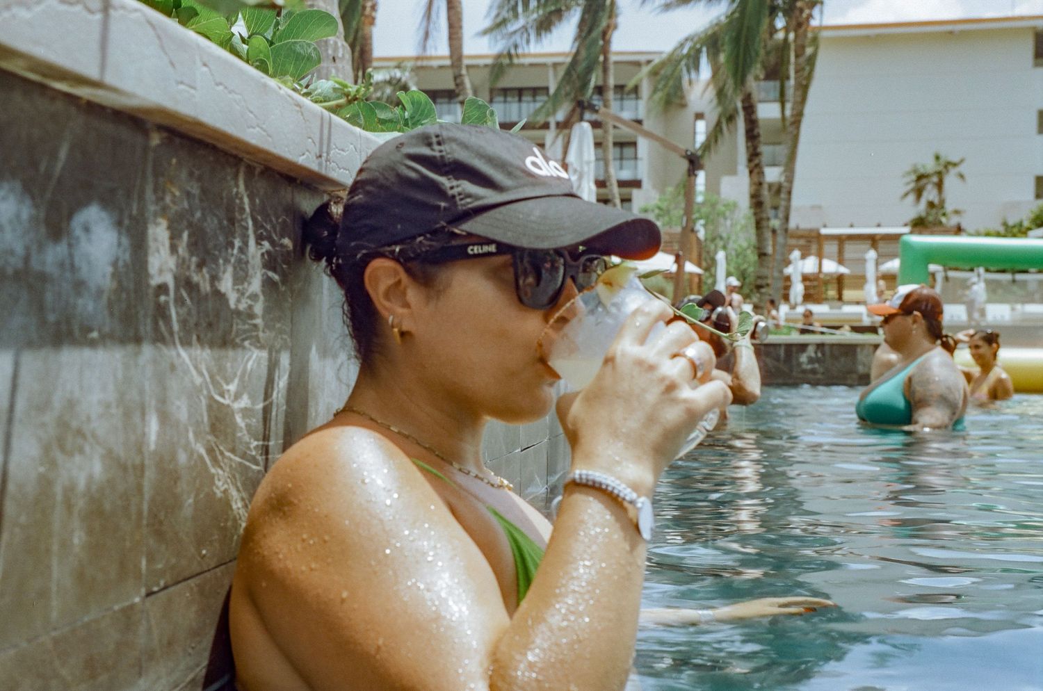 Someone taking a drink while cooling off in a tropical resort pool.