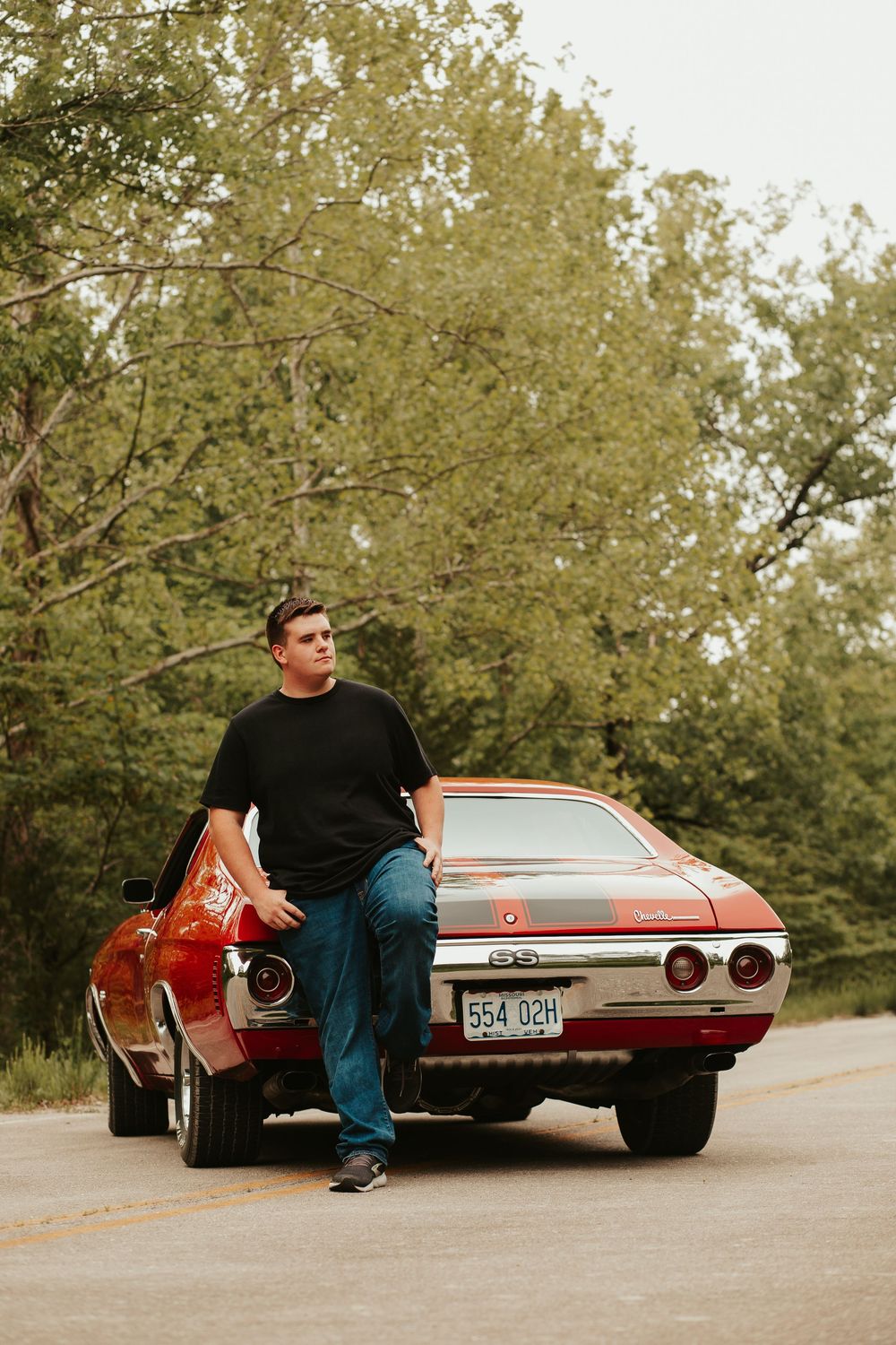 boy posing with a cool red car