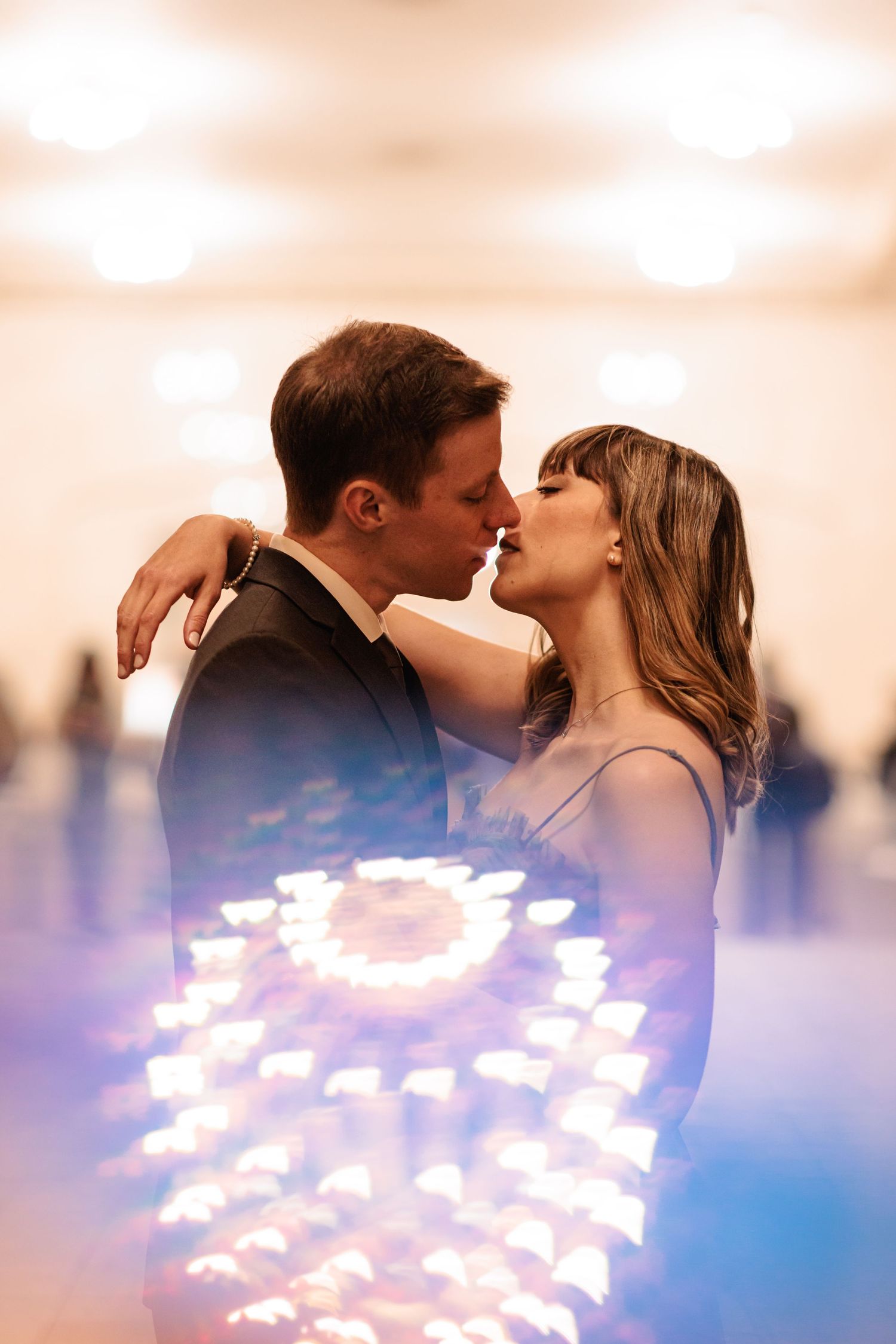 Romantic couple kissing with glowing bokeh lights in soft focus background.
