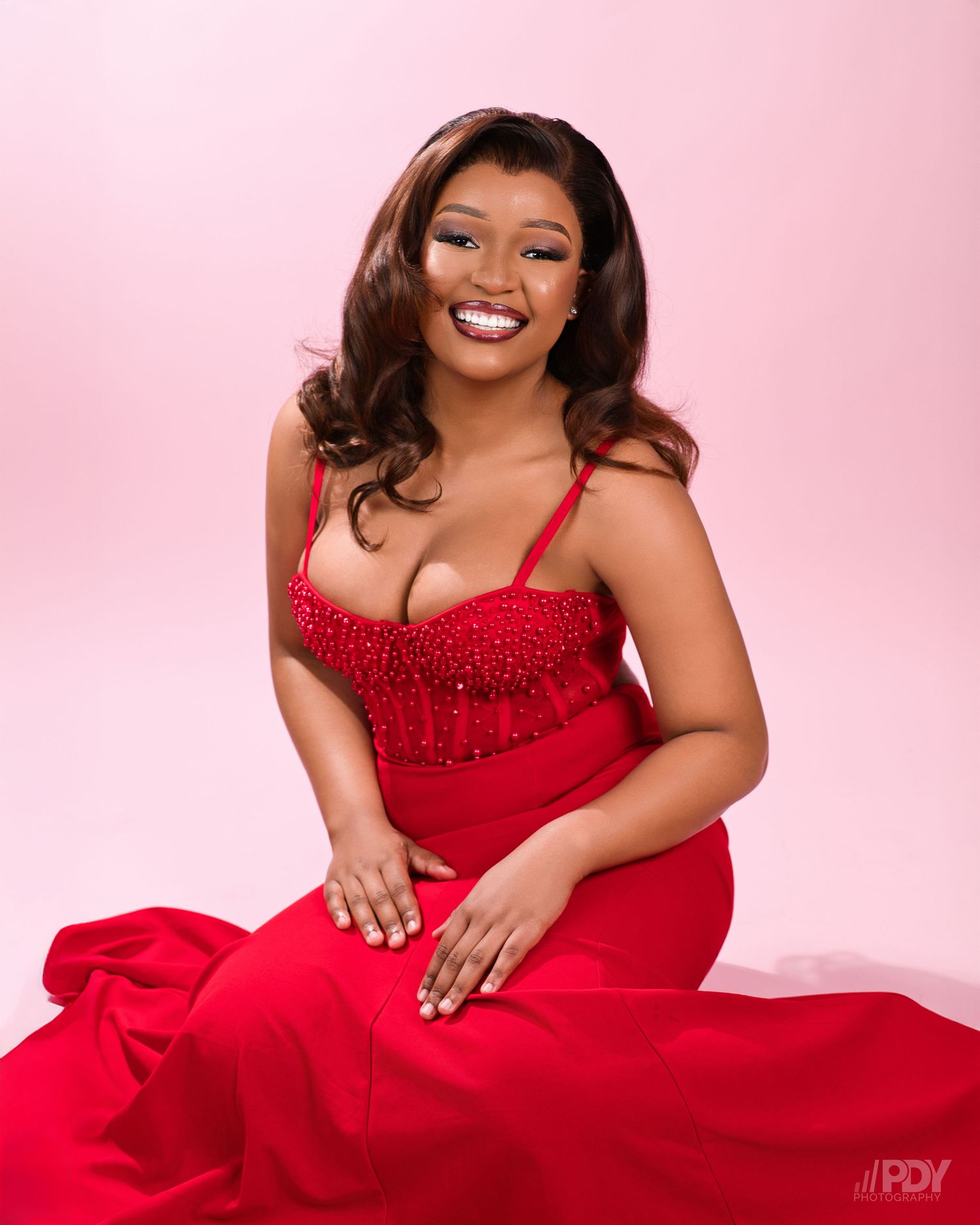 Studio fashion portraits featuring a red formal gown against pink background.