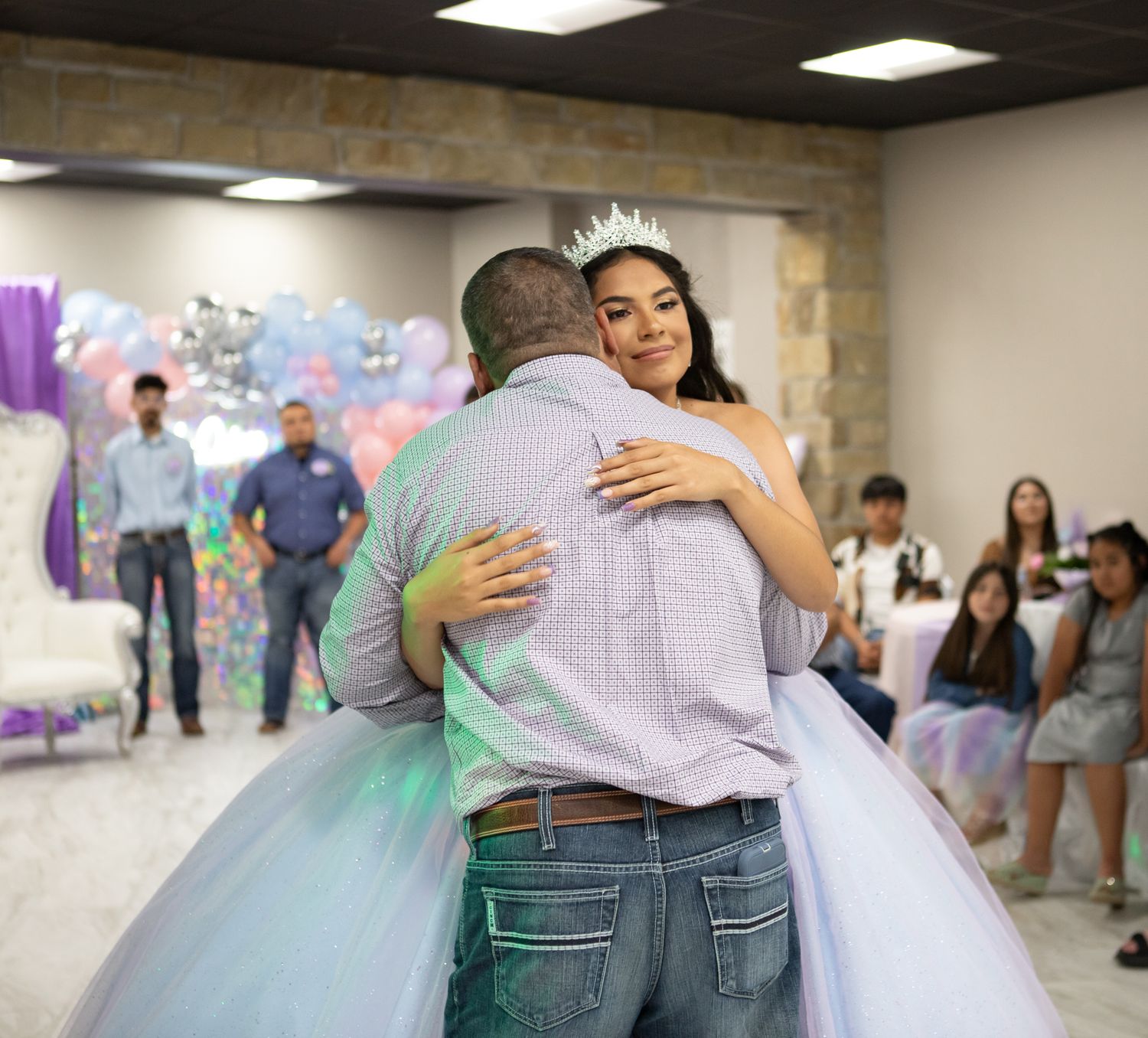 An emotional embrace during a quinceañera celebration with a flowing ballgown.