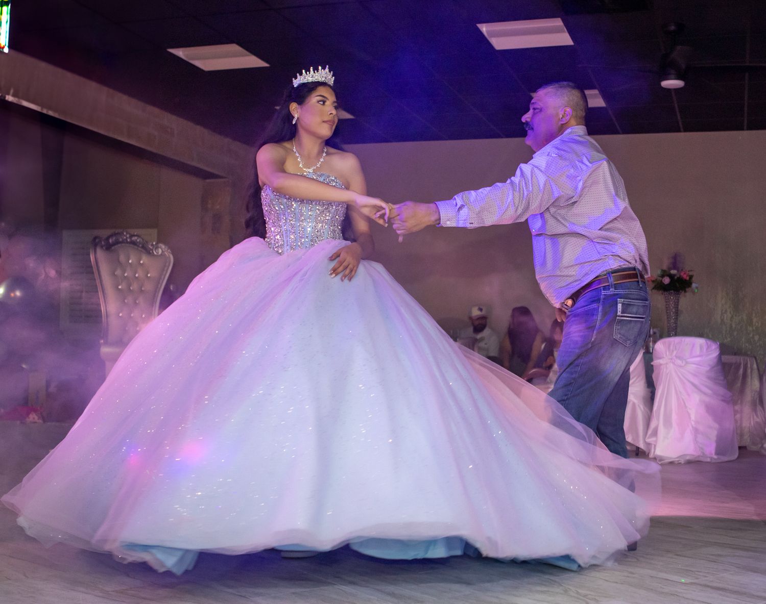 A traditional quinceañera dance with fog effects and dramatic lighting.